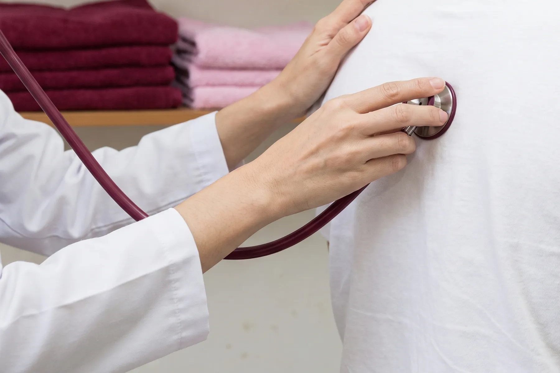 A stethoscope with burgundy tubing placed on a back