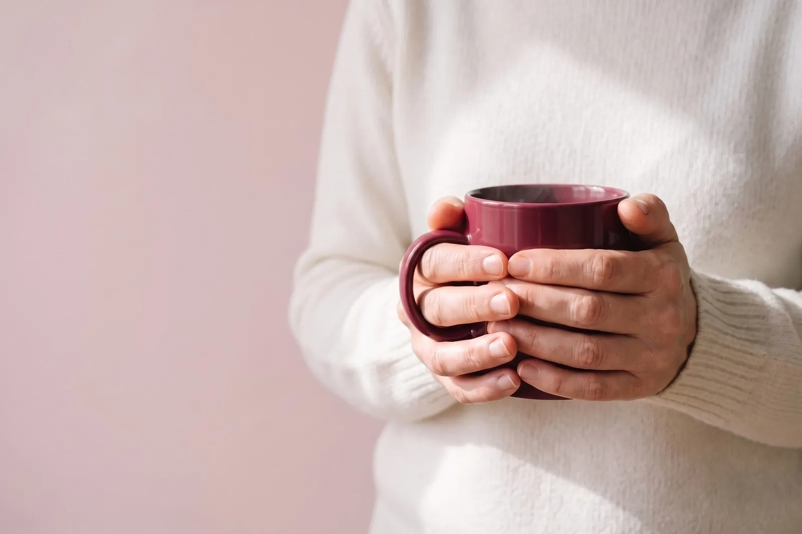 Two hands cupped around a deep red mug