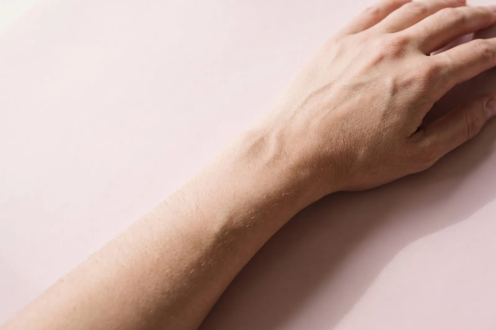 A forearm and the back of a hand resting on a surface